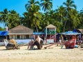 Fishing boats, tropical palm trees, bungalows and street life in Palolem beach Royalty Free Stock Photo